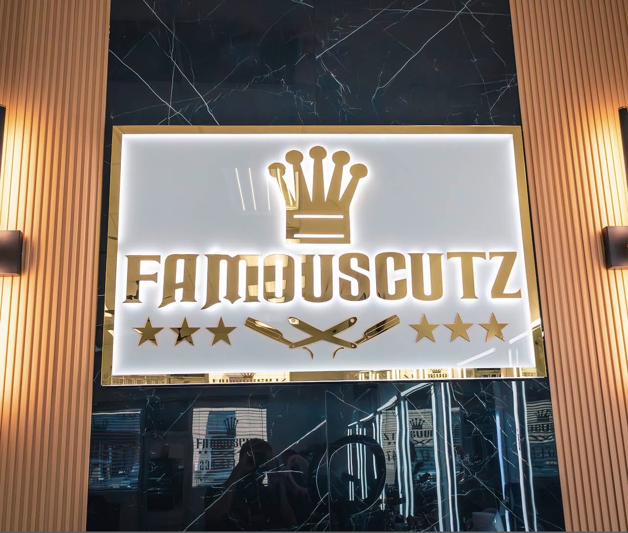 Illuminated gold FamousCutz Barbershop sign inside the Cape Coral shop
